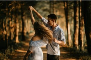 A man and woman dancing in the woods.