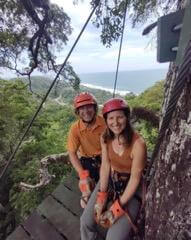 Two people on a zip line in the rainforest.