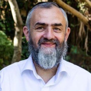 A man with a beard smiling in front of trees, representing marriage restoration.